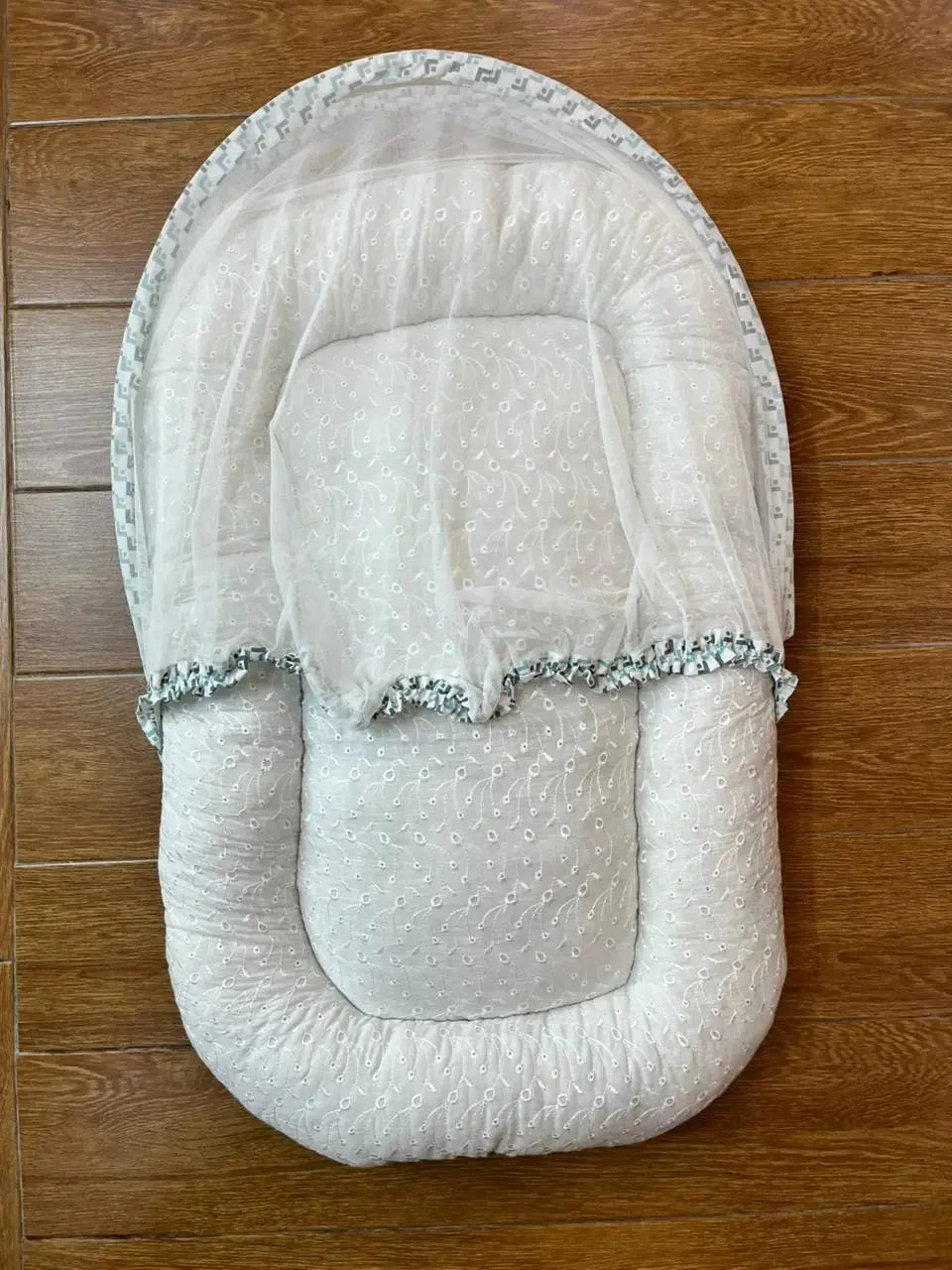 White baby lounger with delicate lace details on wooden floor, Little Flower store product