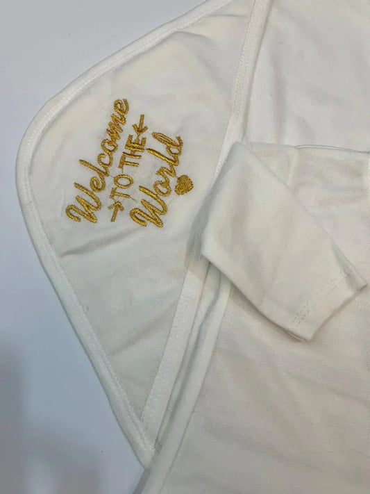 White baby garment with gold 'Welcome to the World' embroidery, Little Flower