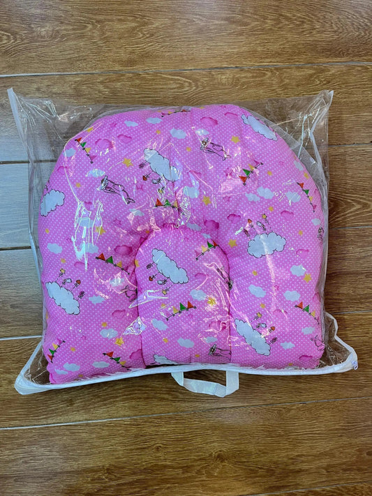 Pink baby pillow with cartoon cloud print in clear plastic packaging on wooden floor