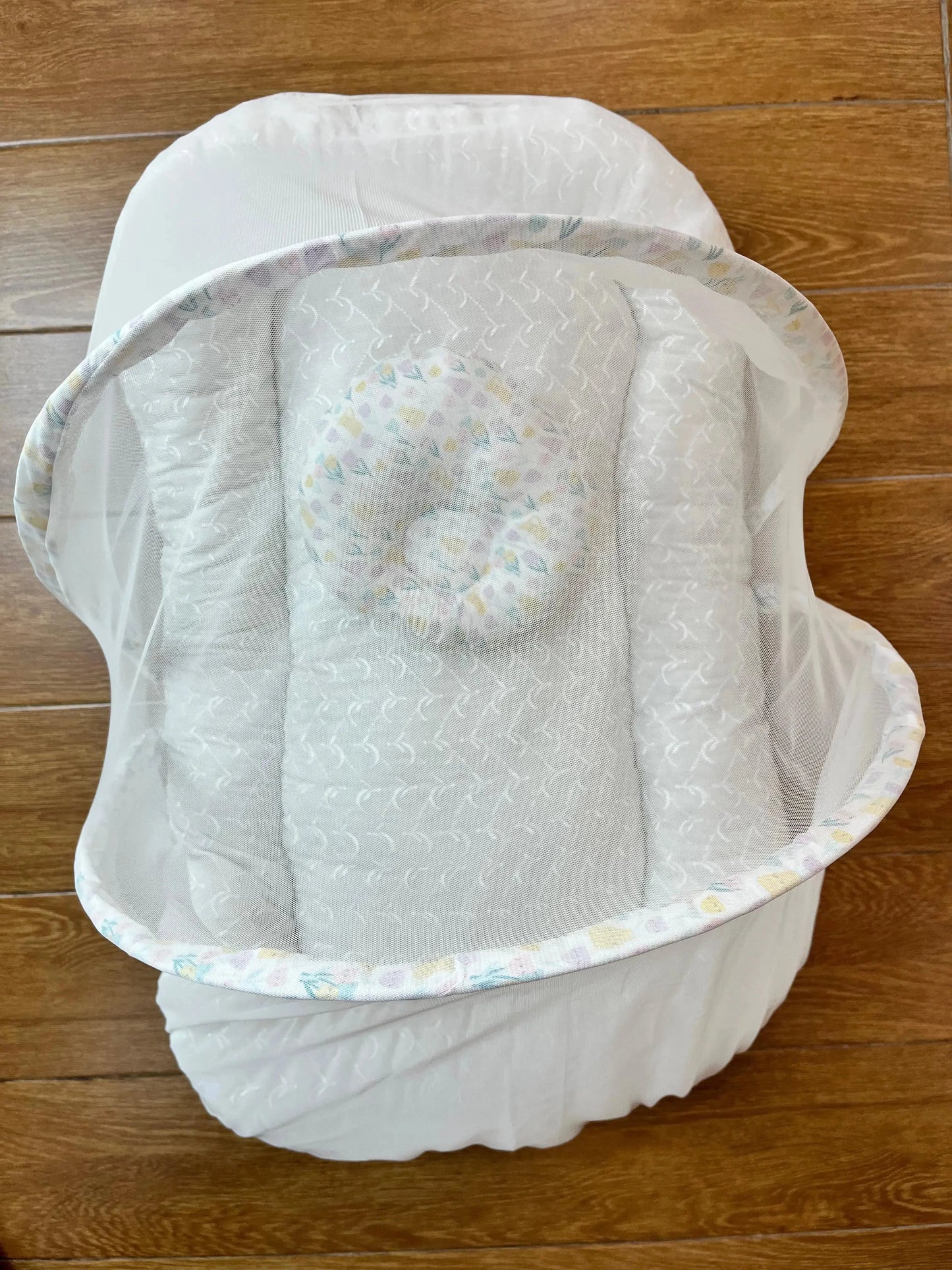 White baby nest bed with mesh cover on wood floor, Little Flower store product