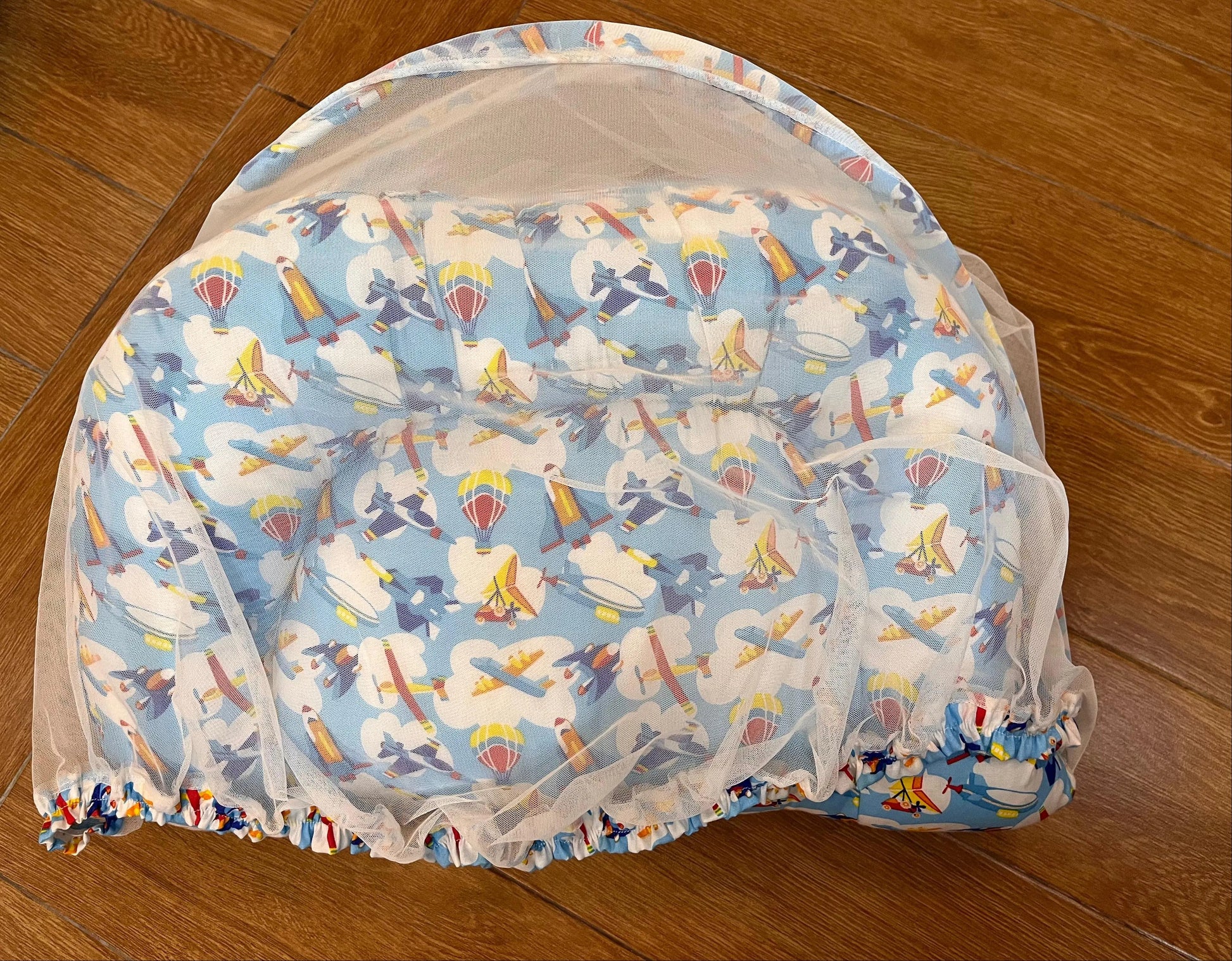 Baby bouncer with cartoon character pattern on a wooden floor