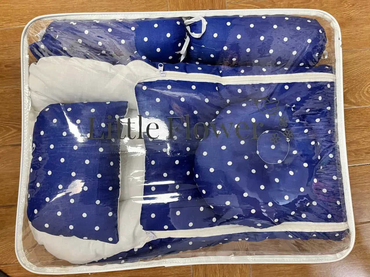 Blue and white polka dot baby seat cover with a clear plastic bag on a wooden floor.
