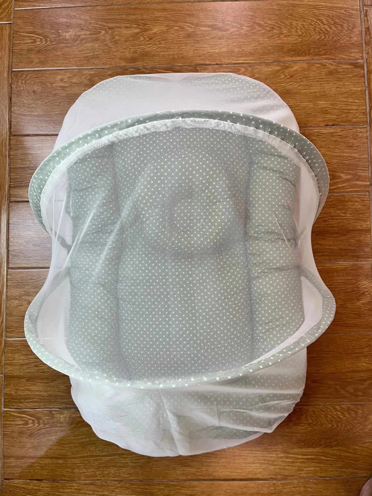 White mesh laundry bag on a wooden floor