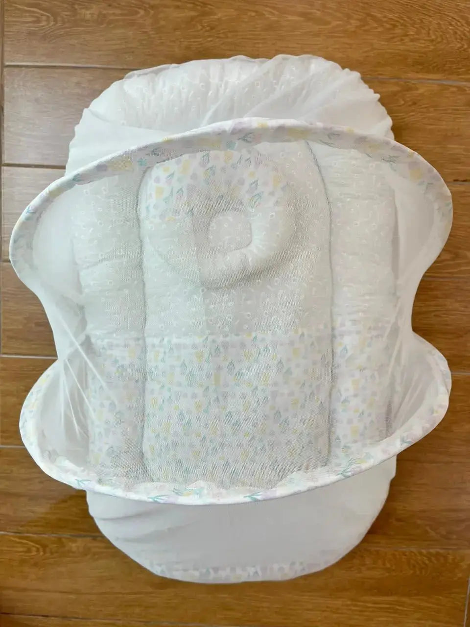 Little Flower baby lounger with net canopy on wooden floor, soft and patterned design